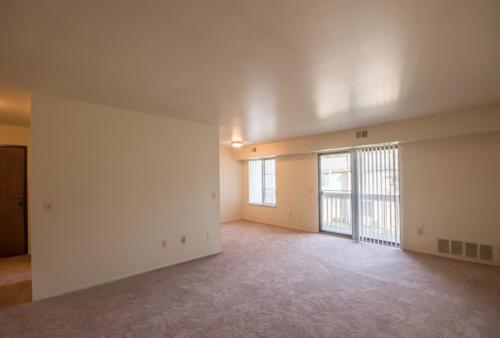 Empty living room with sliding glass doors and carpet.